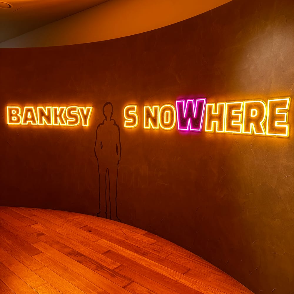 Neon exhibition signage reading BANKSY IS NOWHERE